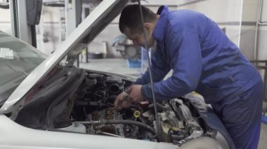 Erkek genç otomatik uzman bir İngiliz anahtarı onarımı veya yapıyor için araba Hood ile fındık sıkın
