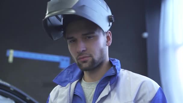 Retrato guapo mecánico de automóviles especialista en casco de soldadura en el fondo del servicio de coche moderno. Movimiento lento — Vídeos de Stock