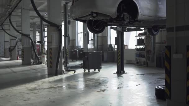 Tankstelle mit reparaturbedürftigen Maschinen. Ein Auto hängt über dem Boden, das zweite ist in der Nähe. — Stockvideo