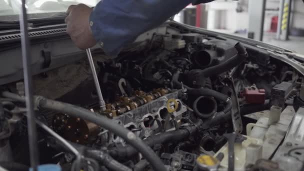 Mannelijke jonge auto specialist scherpt de bouten met een schroevendraaier in de versnellingsbak van de auto bij de planning van de inspectie van de auto — Stockvideo