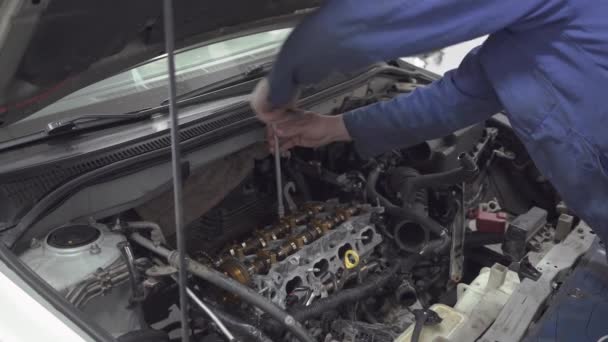 Mecánico experimentado que gira con la ayuda de una herramienta que el motor de un mecánico auto está reparando el coche para que vaya bien . — Vídeos de Stock