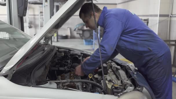 Mantenimiento provisional de automóviles en la estación de servicio. Servicio de coches, reparación, mantenimiento y concepto de personas - mecánico que trabaja en el taller — Vídeo de stock