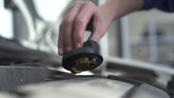 Рабочий механик вкручивает важную деталь клапона в капот автомобиля после тестирования в автосервисе. Закрыть — стоковое видео