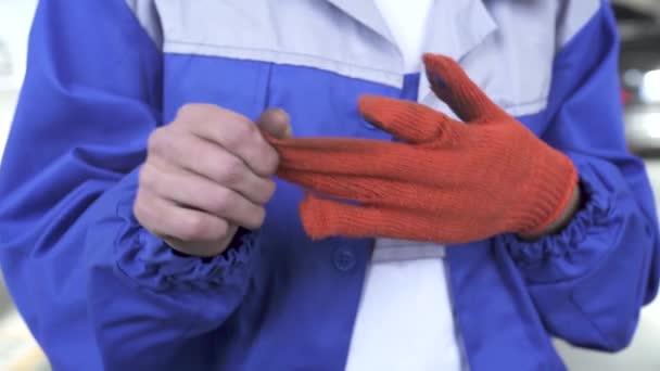 Auto monteur specialist verwijdert vuil oranje handschoenen na het werk met machines en vuile handen toont in mazol — Stockvideo