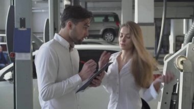 Çok kadın Yöneticisi yakışıklı istemci makine onarım sözleşme ve gülümsüyor arabayı hizmetindeki doldurmak nasıl söyler.