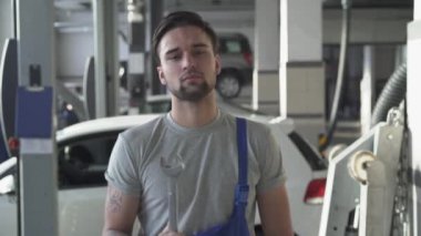 Bir İngiliz anahtarı duran arabayı hizmetindeki iplik üniformalı yakışıklı sakallı otomatik mekanik portresi.