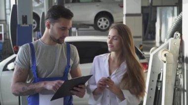 Otomatik servis, tamir, anlaşma ve insanlar kavramı - mekanik ve müşteri ya da araba sahibi imza kağıt Atölyesi'nde el sallıyor. Tatlı gülümseyen kız araba anahtarlarını bir güzel otomatik mekanik verir..
