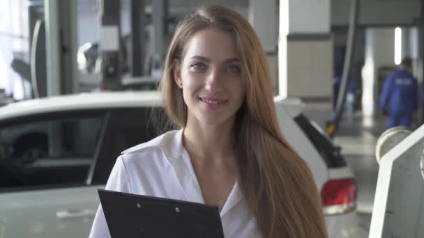 Retrato de jovem sorrindo mulher bonita gerente ou cliente com contrato no fundo do serviço de carro — Vídeo de Stock