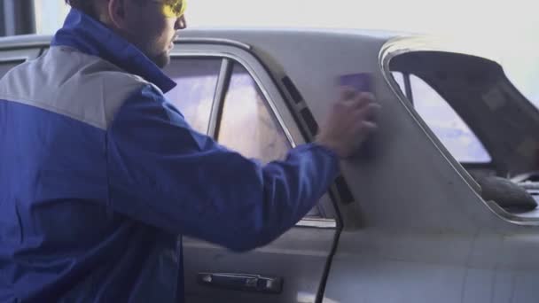 Joven auto especialista puliendo el coche con gafas especiales y uniforme en el servicio de coche moderno — Vídeos de Stock