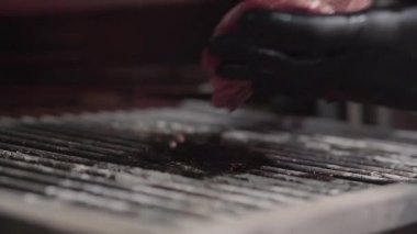 El Cook siyah eldiven koyar parça et ızgara kaburga ile kapatın. Şef taze sulu et ızgara koyar. Ağır çekim. Modern bir restoranda yemek hazırlama kavramı