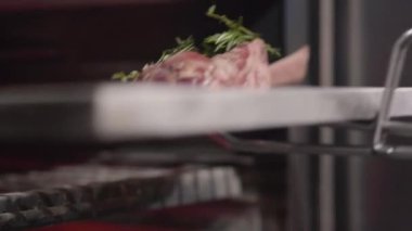 El siyah eldiven koyar parça et Cook metal aracını kullanarak fırında kaburga ile kapatın. Şef taze sulu et ızgara fırın itin. Modern bir restoranda yemek hazırlanıyor. Ağır çekim