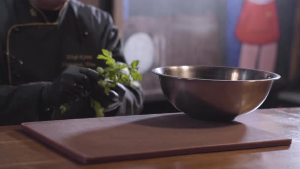 シェフのぼやけた姿涙パセリの葉と、大きなアルミのボウルを置きますをクローズ アップ。モダンなレストランでの食事の準備 — ストック動画