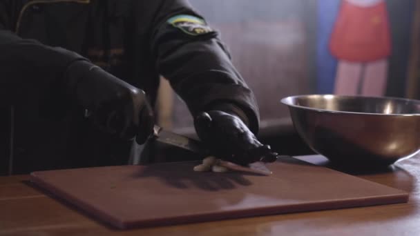 Шеф-повар дробления острым металлическим ножом ароматический чеснок на деревянной доске, чтобы подготовить маринад в большой пластины — стоковое видео