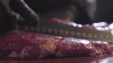 Elinde Şef siyah eldiven küçük kesikler çiğ sulu et üzerinde büyük bıçak ile yakın yapma yemek. Restoran gıda hazırlama