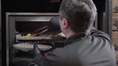 Şef siyah eldiven balık hazır değildir, ancak sadece dolmalık biber, kırmızı biber biber ve limon, pişmiş sıcak fırın ızgara dışarı çeker