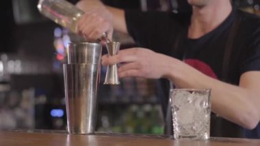 Shaker kullanarak ve bir alkol ile farklı kokteyl yapmak yakışıklı barmen mixologist güzel modern barda içecekler. Yakın çekim