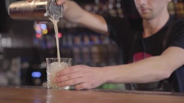 Barmen dökme yumurtadan kokteyl cam daire dönüm buz ile shaker metal. Genç adam barda lezzetli kokteyl yapmak