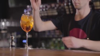 Genç barmen ferahlatıcı bir viski ya da alkol kokteyl bardağına buz ile karıştırma. Yakın çekim.
