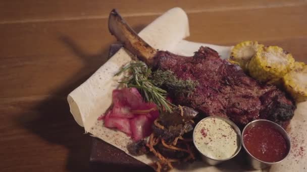 Carne grelhada com osso de costela deitado no pita com repolho vermelho, milho, cogumelos, cenoura e molhos de perto. Servindo comida no restaurante . — Vídeo de Stock