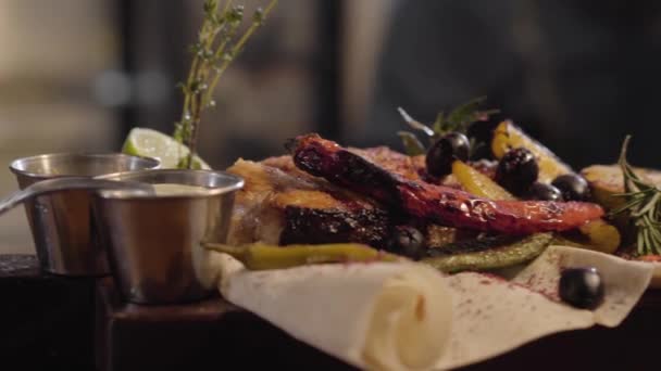 Close-up van gegrilde zalm vis geserveerd met sauzen, kruiden, olijven, chilipeper, limoen en citroen liggend op pita close-up. Bereiden en serveren van eten in een restaurant — Stockvideo