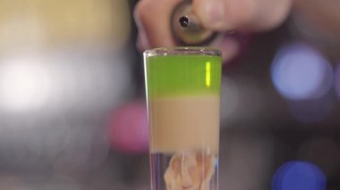 Barmen dökülen şurubu Shot el alkol içki iki kat ile kapatın. Barda çok katmanlı alkollü kokteyl hazırlama sürecinin pub. Kamera aşağı taşır