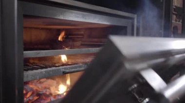 Siyah lateks eldiven açık ızgara fırında pişirin ve çeker ile metal aracını kullanarak ateş et parçası dışarı kapatın. Şef son yemek. Gıda hazırlama bir restoran