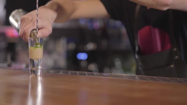 Μπάρμαν ρίχνει ένα δροσιστικό ποτό ή κοκτέιλ αλκοόλ σε ένα μικρό ποτήρι. Κοντινό πλάνο. — Αρχείο Βίντεο