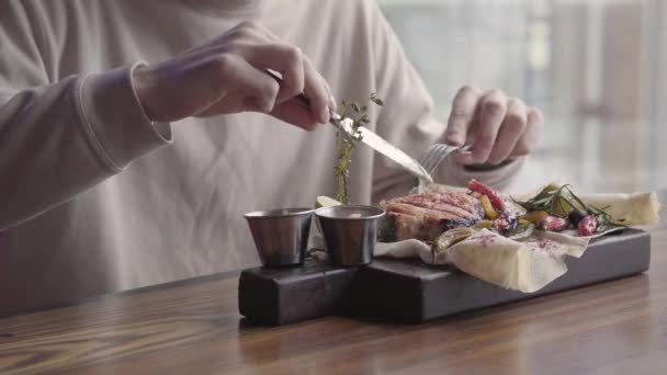 Chico guapo sentado en un restaurante de lujo y comiendo impresionante plato delicioso con pescado y verduras a la parrilla — Vídeos de Stock