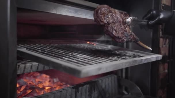 Готовит руки в черных резиновых перчатках шеф-повара переворачивая сочный кусок жареного мяса в духовке . — стоковое видео