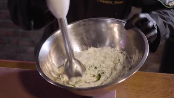Detailní záběr rukou šéfkuchaře v vaříme černé gumové rukavice šlehačky s petrželkou pomocí mixéru velké hliníkové mísy zblízka. Příprava omáčky v moderní restauraci — Stock video