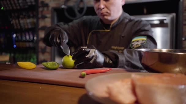 Chef che taglia con il coltello affilato lime sul bordo di legno per preparare l'insalata nel piatto grande — Video Stock