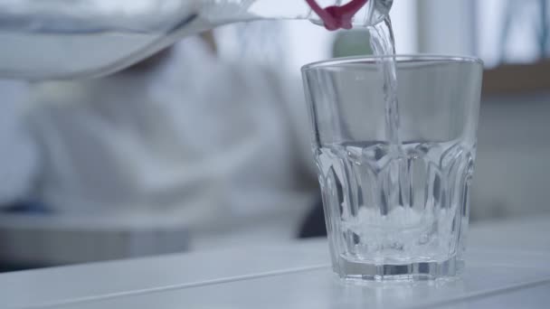 Agréable serveur verser de l'eau potable dans un verre avant d'apporter le plat principal, et le gars le prend dans ses mains et les boissons. Gros plan 