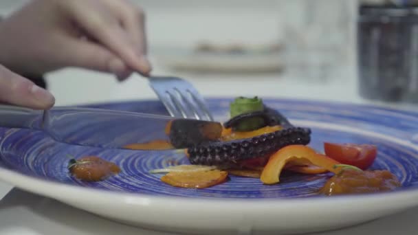 Mulher comendo polvo apetite maravilhosamente servido e legumes frescos grelhados no prato azul. Fechar — Vídeo de Stock