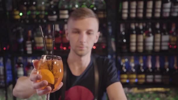 Jeune barman dans le restaurant mettre un verre de vin au bar avec cocktail jaune et orange à l'intérieur — Video