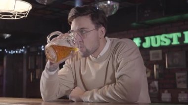 Yakışıklı genç sakallı adam mutlu televizyonda futbol maç izlerken barda bira sahip gülümseyen yakın çekim. Barda yalnız alkol rahatlatıcı futbol takımı hayranıyım
