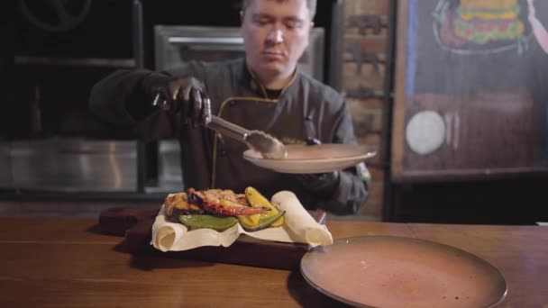 Chef in guanti neri che serve su legno appena cucinato delizioso pesce succoso con peperoni alla griglia, peperoncino piccante e lime. Da vicino. — Video Stock