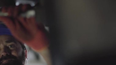 Tamir istasyonunda kaldırılan özel bir araçla arabanın detaylarını siken profesyonel bir tamirci. Üniformalı yetenekli adam araba tamir ediyor. Araba servisi, tamirat.