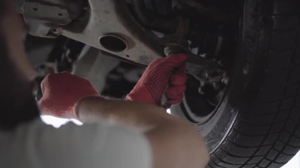 Professionelle Kfz-Mechaniker Schrauben Details des Autos mit Spezialwerkzeug auf angehobenen Automobil in der Reparatur-Service-Station aus nächster Nähe. Geschickter Mann in Handschuhen repariert Auto. Auto-Service, Reparatur-Wartung. — Stockvideo