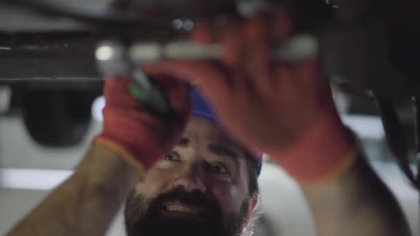 Professionnel barbu mécanicien de voiture vissage détails de la voiture avec outil spécial sur l'automobile relevée à la station-service de réparation de près. Homme habile en uniforme réparateur de voiture. Service de voiture, entretien de réparation — Video