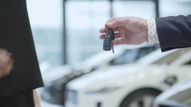 Mužské ruce dává auto klíče k famale ruku v autodům zblízka. Nerozpoznaný auto prodejce a žena, kteří si koupili vozidlo potřást rukou. — Stock video