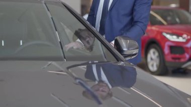Arabanın içinde modern Bayilik seçerek iş adamı. Auto show odasında hassasiyet ile ayna modern otomobil dokunmadan takım elbiseli tanınmayan adam kapatın. Kavramı bir araç satın alma