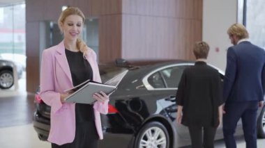 Pembe ceket araç seçimi çift önünde araba hakkında bilgi ile büyük kitap seyir hoş kadın portresi. Konsept otomobil, otomatik iş satın alma