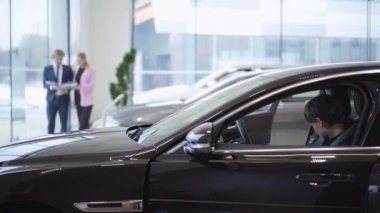 Kendine güvenen kadın işadamı ve pazarlamacı discussind sözleşme bulanık rakamlar yürüme önünde arabada oturan kısa saçlı. Modern kız motor Show'da otomobil seçimi