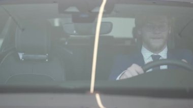 Yolcu Kabini yeni arabanın içinde yakışıklı sakallı adam. Başarılı adam yeni otomatik inceliyor. Araba Bayilik.