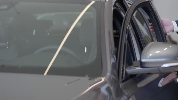 Впевнений бородатий чоловік у костюмі і окулярах відкриває двері водіїв у своїй машині, сидить всередині і дивиться в дзеркало заднього виду. Бізнесмен в костюмі розкішного чорного автомобіля. Концепція успішної людини — стокове відео