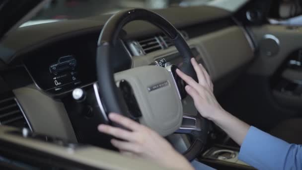 妇女用双手抚摸方向盘, 并近距离触摸控制面板。现代女孩在车展中检查汽车。购买汽车的概念, 汽车业务。相机向右移动 — 图库视频影像