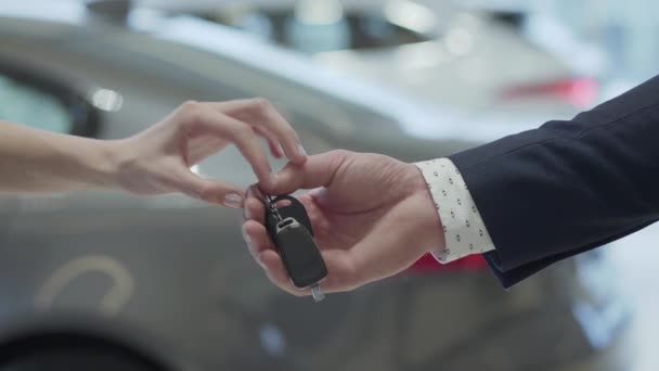 男性の手は、車のディーラーで女子の手にキーをクローズ アップ車を与えます。認識できない自動販売車両を買った女性が手を振る. — ストック動画
