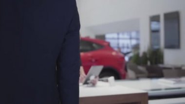 Uzun boylu adam masada oturan kendine güvenen satıcı kadın gelir. Kadın modern Otomobil Fuarı adam müşteri tablet için bilgileri gösterir. Araba showroom çalışma pazarlamacı
