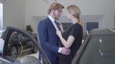 Mutlu bir adam ve kadın modern Otomobil Fuarı araba aldım. İki otomobil ile bir araba Bayilik açılan kapıdan yakınındaki sarılma. İşadamı karısı için satın alma aracı