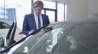 Otomobil Fuarı yeni otomobil modeli tartışırken yakışıklı genç araba satıcısı. Araba Bayilik.